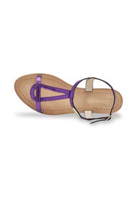 Sandale strappy métallisée violette avec une semelle plate, dotée d'une sangle arrière beige et d'un design en T. Doublure intérieure lisse avec des détails de couture.