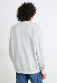 Grå crewneck sweatshirt med lange ærmer, blødt bomuldsmateriale, ribbede manchetter og kant, samt en afslappet pasform. Bruges sammen med blå denimjeans.