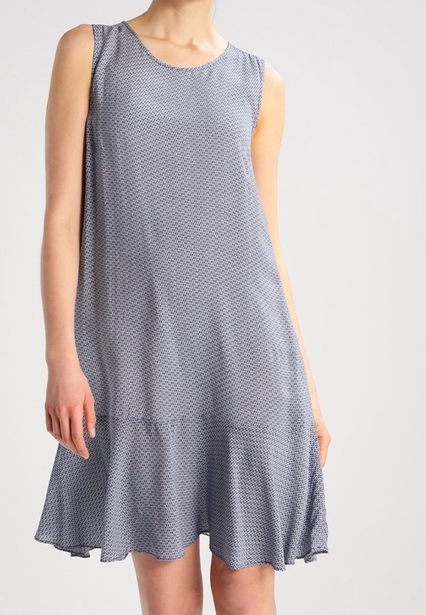 Bezramenné šaty z modré látky se strukturovaným vzorem. Rozšířený střih s volánem na spodním lemu, dosahujícím do poloviny stehna. Hladká textura po celém povrchu.