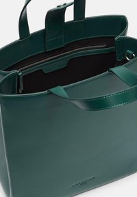 Zielona torba na ramię ze skóry o usztywnionej konstrukcji, wewnętrzna kieszeń na zamek i płaskie uchwyty. Charakteryzuje się gładką fakturą i tłoczonym logo marki.