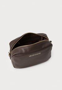 Borsa in pelle marrone con texture, zip e branding in tono oro, con forma arrotondata e spazioso interno dotato di più scomparti.