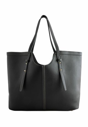 Sac cabas en cuir noir avec deux longues anses, coutures blanches et rivets dorés sur des sangles réglables.