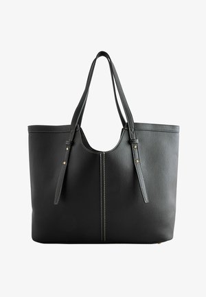 Sac cabas en cuir noir avec deux longues anses, coutures blanches et rivets dorés sur des sangles réglables.