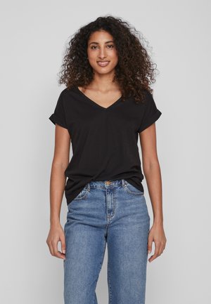 T-shirt noir à col en V avec des manches courtes retroussées, fabriqué en tissu doux. Associé à un jean bleu taille haute avec un design classique à cinq poches.