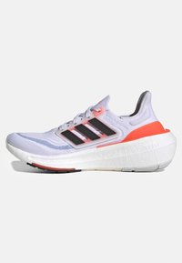 Buty do biegania Adidas z białą siateczkową cholewką, czarnym logo w postaci trzech pasków, różowymi akcentami oraz teksturowaną białą podeszwą z oznaczeniem "Lightboost".