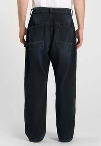 Zwarte denim broek met een relaxte pasvorm, voorzien van dubbele achterzakken en riemlussen. De textuur is stevig met een gladde afwerking.
