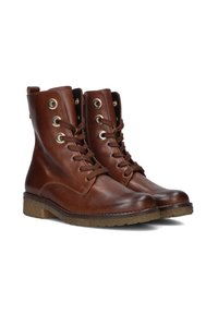 Een paar bruine leren enkelboots met vetersluiting en metalen oogjes, voorzien van getextureerde rubberen zolen en zijritsen.