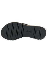 Czarna, teksturowana gumowa podeszwa z poziomymi rowkami i wytłoczonym logo. Charakteryzuje się zakrzywionym kształtem i zróżnicowaną głębokością dla lepszej przyczepności.
