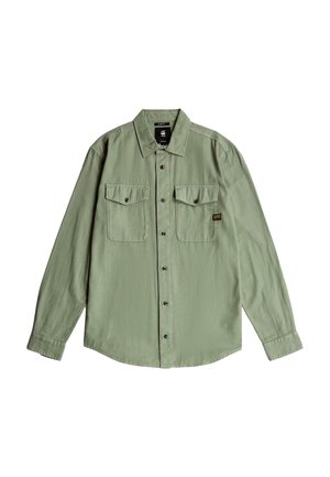Hellgrünes, langärmliges Hemd mit Knöpfen, zwei vorne aufgesetzten Brusttaschen mit Knöpfen und einem kleinen schwarz-gelben Etikett auf der linken Tasche.