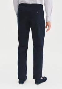 Granatowe, proste spodnie o gładkiej teksturze materiału, z tylnymi kieszeniami ozdobionymi guzikami i subtelnym połyskiem.