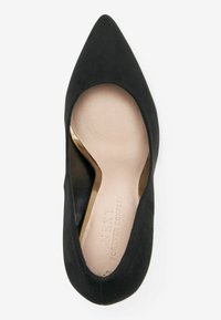 Chaussure plate noire à bout pointu pour femmes avec semelle intérieure beige et inscription "NEXT FOREVER COMFORT" embossée à l'intérieur.