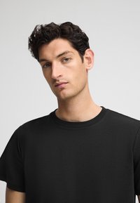 Zwarte katoenen T-shirt met een ronde halslijn en korte mouwen, met een gladde textuur en een minimalistisch ontwerp.