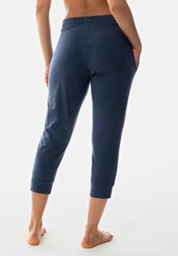 Navyblauwe capribroek gemaakt van zacht, rekbaar materiaal met een getailleerd ontwerp, elastische tailleband en zijzakken. Over het algemeen een gladde textuur.