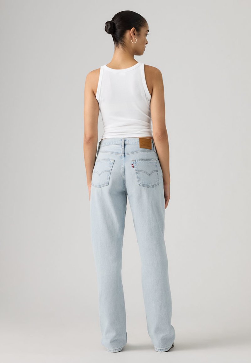 Jean en denim bleu clair avec une coupe droite, doté d'un patch en cuir sur la ceinture arrière et de deux poches plaquées à l'arrière.