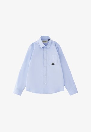 Camicia azzurro chiaro a maniche lunghe con bottoni, colletto a punta e taschino sul petto con una piccola toppa nera a forma di diamante.