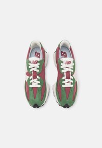 Sportovní boty s horní částí ze zeleného semiše a bordó akcenty, bílé tkaničky a texturovaná černá gumová podešev. Logo "NB" na jazyku.