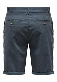 Shorts bleu foncé en tissu texturé, avec deux poches arrière et un ourlet retroussé. Petits accents matériels ronds sur les poches.