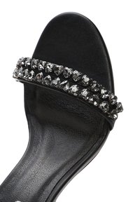 Sandalia de slide negra con un acabado de cuero suave y una doble fila de adornos de strass claros en la correa.