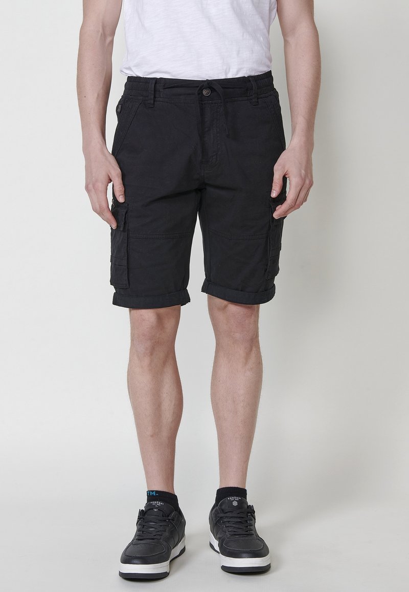 Shorts cargo noirs avec revers, en tissu de coton mélangé. Comprend plusieurs poches et une taille élastique avec cordon de serrage.