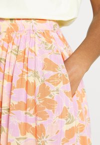 Blommig kjol i orange, rosa och beige färger. Tillverkad av lättviktig tyg med veck och sidofickor.