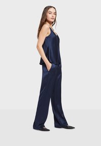 Nawigacja satynowa koszulka i szerokie spodnie, z lekko opadającym krojem, gładką teksturą i kieszeniami po bokach. Czarne płaskie buty dopełniają zestaw.