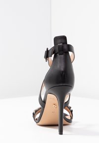 Musta nahkainen korkokenkä nilkkahihnalla ja soljella, ohut stiletto-korko ja koristeelliset niitit etuhihnoissa, koko 37.