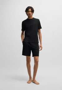 Zwarte getextureerde t-shirt met een ronde hals en korte mouwen, gecombineerd met zwarte getextureerde shorts, beiden met minimale branding.