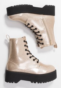 Gouden glitter enkellaarsjes met zwarte veters, zijrits en dikke zwarte zool; gladde textuur en glanzende afwerking. Voorzien van een trekbandje.