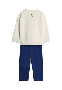 Biela mikina s dlhým rukávom s logami Adidas a Marvel v kombinácii s modrými nohavicami, zobrazená zozadu.