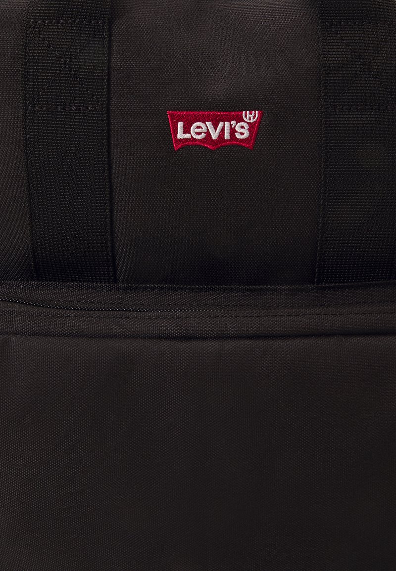 Schwarzer Stoff-Rucksack mit einem roten gestickten Levi's-Logo, einer mit Reißverschluss versehenen Tasche und strapazierfähigem synthetischem Material.