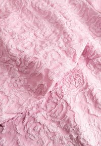 Lyserødt blomstret blonderstof med fremhævet struktur og indviklede rosemønstre. Blødt, let materiale med et delikat udseende.