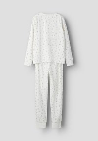 Ensemble de pyjama blanc à manches longues avec un motif floral ; le haut a un col arrondi et le pantalon est doté de poignets élastiques aux chevilles.