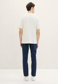 Vit kortärmad texturerad skjorta, lös passform, ihop med marinblå skräddarsydda byxor och vita sneakers. Enkelt och modernt design.