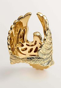 Anillo en tono dorado con un diseño texturizado de hoja. Presenta patrones recortados y una forma esculpida. Superficie reflectante con detalles intrincados.