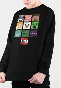 Felpa nera con un design in pixel art che presenta vari volti di personaggi in tema videoludico. Polsini e orlo inferiore a coste.
