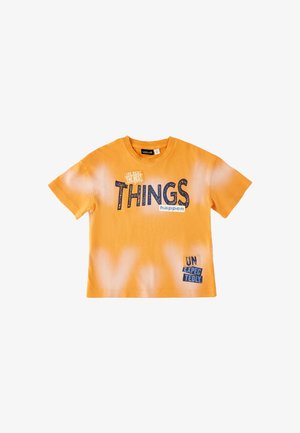 Maglietta arancione a maniche corte con macchie bianche di candeggina e testo "Le cose migliori accadono" e "Inaspettato" stampati in blu e bianco.