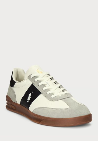 Valge ja hall suedesneaker mustade aktsentidega, nööridega disain, logodetail küljele ja kummitald. Lamedad nöörid ja pehmendusega krae.