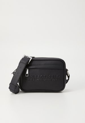 Bolsa de ombro em couro preto com logótipo em relevo, fecho com zíper, alça ajustável e superfície texturizada. Forma retangular compacta.