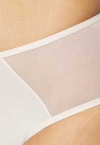 White underwear with a mesh panel, featuring a smooth texture and contrasting matte finish along the edges. Subtle transitions between materials.