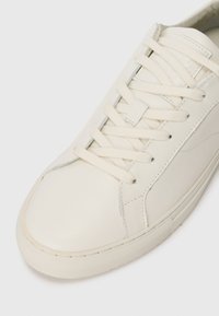 Hvite lær sneakers med myk tekstur, rund tå, flate snøringer og subtile sømdetaljer; gummiyttersåle med teksturert grep.