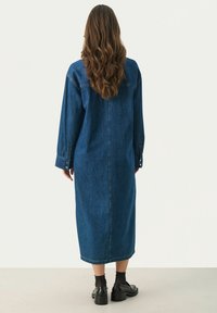 Denim-mekko, pitkä ja löysä malli, tummansininen väri, pitkät hihat, napitettu hihansuu, polven puoliväliin asti ulottuva pituus, teksturoitu kangas, minimalistinen suunnittelu.
