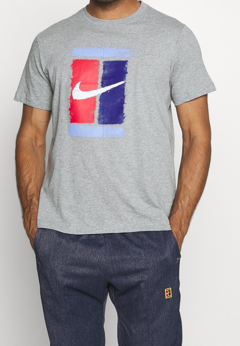 Graues T-Shirt aus Baumwolle mit einem bunten, abstrakten Design in Rot, Blau und Hellblau sowie einem weißen Nike Swoosh Logo.