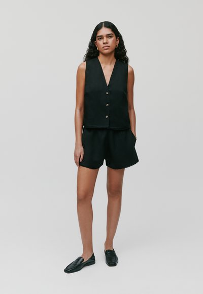 Zwarte mouwloze top met een v-hals en knoopsluiting, gecombineerd met bijpassende zwarte shorts. Soepele stof met een comfortabele pasvorm.