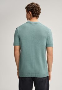 Maglione a maniche corte di colore verde menta, lavorato a maglia, con colletto e orlo a costine, caratterizzato da una finitura testurizzata e una vestibilità rilassata.