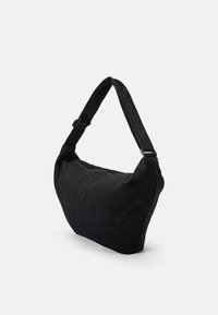 Bolsa de ombro em cordura preta com formato curvado, alça ajustável e fecho com zíper. O tecido texturizado acrescenta profundidade ao design.