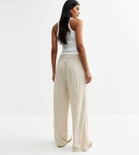 Pantalons larges beiges avec une coupe décontractée, taille élastique et tissu léger. La texture semble lisse avec un subtil éclat.