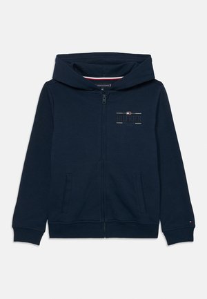Marineblauer Hoodie mit Reißverschluss, Fronttaschen, Kapuze und kleinem eingesticktem Tommy Hilfiger-Logo auf Brust und Ärmelbündchen.