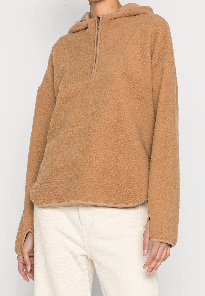 Felpa in pile color nocciola con colletto a mezza zip, caratterizzata da una superficie morbida e testurizzata e da un fit rilassato. Accentuata da un orlo arrotondato e spalle scese.
