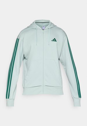 Lichtgroene zip-up hoodie met een trekkoordcapuchon, met donkergroene drie-strepen accenten op de mouwen en een klein groen logo op de borst.