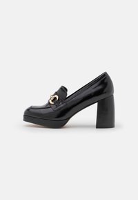 Black patent leather heeled loafers with a rounded toe, square block heel, and a gold accent buckle. Smooth surface and sleek design.